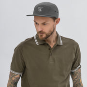 Man wearing a stylish five panel cap with a polo shirt, showcasing modern streetwear fashion.