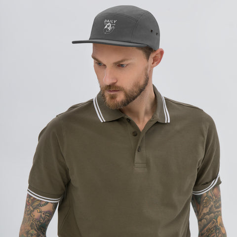 Man wearing a stylish five panel cap with a polo shirt, showcasing modern streetwear fashion.