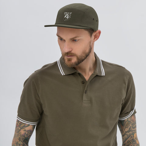 Man wearing a stylish five panel cap and a polo shirt, showcasing casual streetwear style.