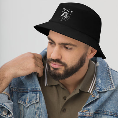 Man wearing a stylish black bucket hat with daily club logo, paired with a denim jacket.