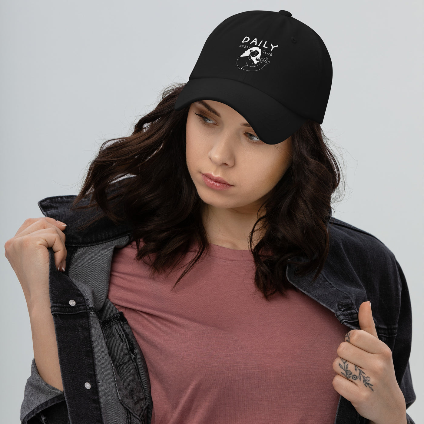 Black dad hat with daily print worn by a woman, styled with a casual outfit and denim jacket.
