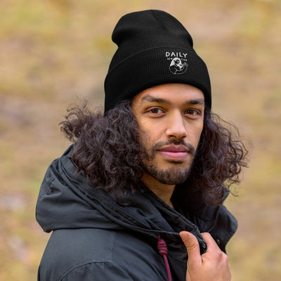 Young man wearing a black cuffed beanie outdoors, showcasing warmth and style in winter fashion.