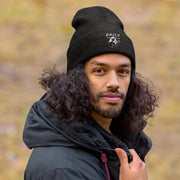 Man wearing a black cuffed beanie with logo outdoors, showcasing warmth and style for winter wear.