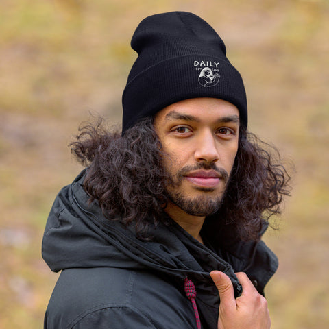 Stylish man wearing a black cuffed beanie in nature, showcasing warmth and comfort for winter fashion.