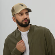 Man wearing a stylish trucker cap with a mesh back, featuring a logo, paired with a casual olive jacket.