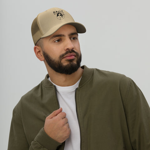 Man wearing a stylish trucker cap with a mesh back, featuring a logo, paired with a casual olive jacket.